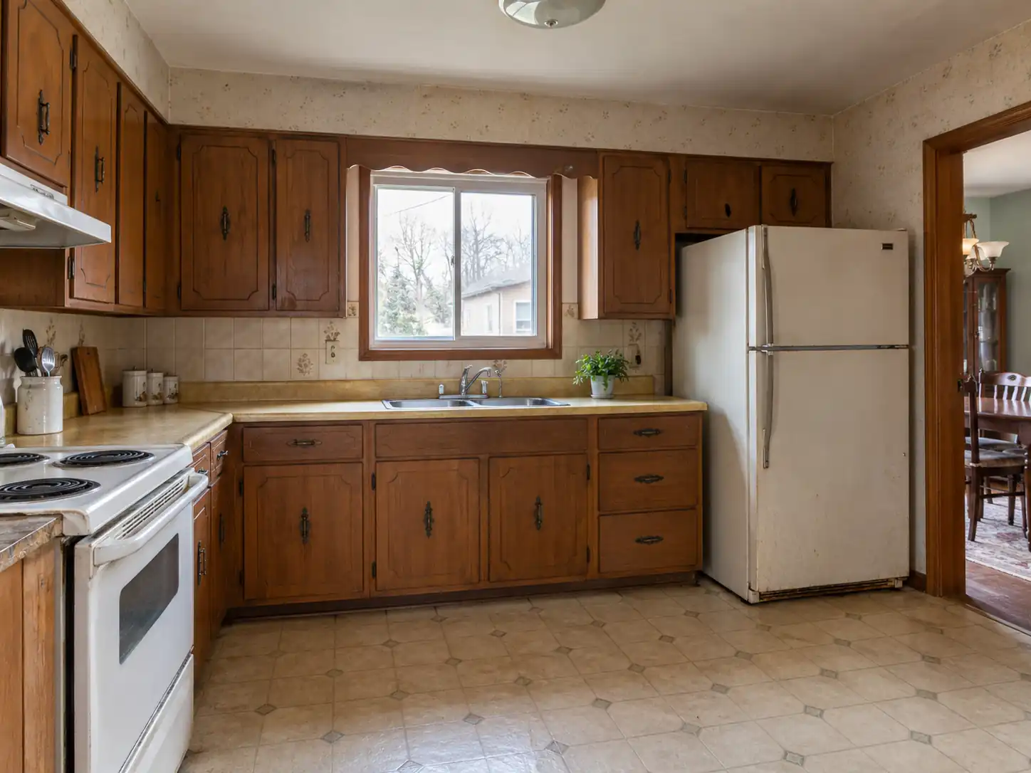 Outdated kitchen with old wooden cabinets and appliances that need renovation